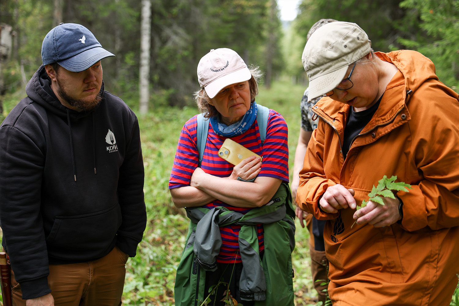 Erä- ja luonto-opasopiskelijat tarkastelevat kasvia metsässä osana luonnontuntemuksen harjoitusta.