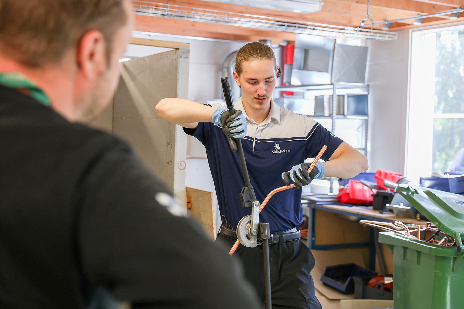 Jone Holopainen taivuttaa kupariputkea WorldSkills-valmennuksessa.