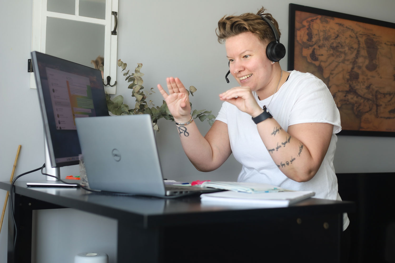 Tiina Åberg on kannettavan tietokoneen edessä kädet ylhäällä elehtien ja hymyillen.