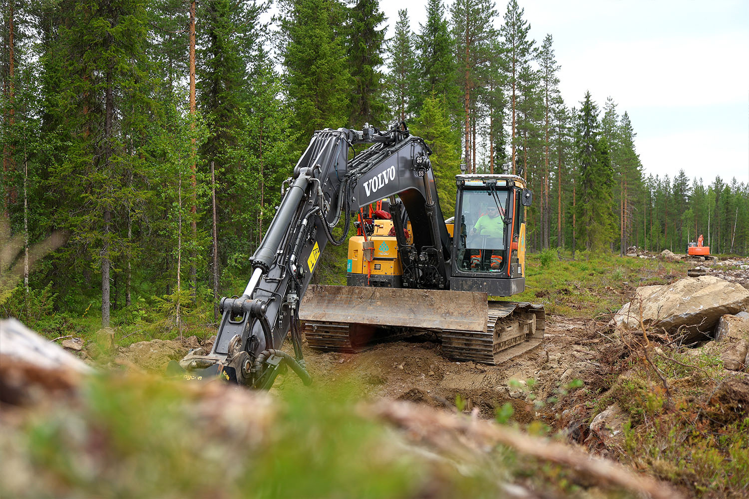Kaivinkone työskentelee metsäisessä maastossa Tuomijärven ajoharjoitteluradan rakennustyömaalla.